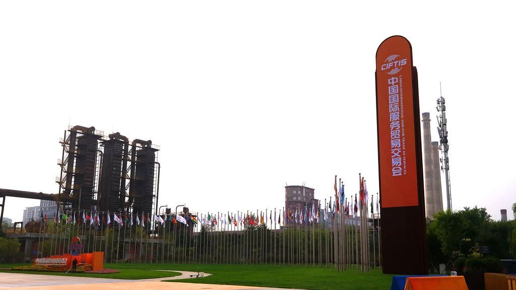 Entrada de um centro de exposições de Pequim com bandeiras e totem de uma feira internacional