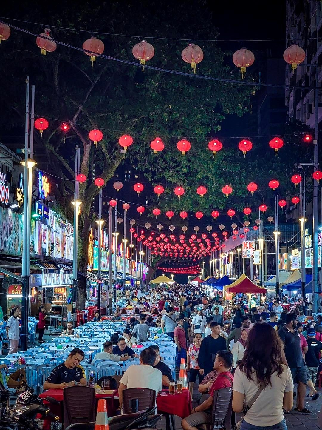 Rua Jalan Alor à noite, com lanternas vermelhas e mesas de restaurantes
