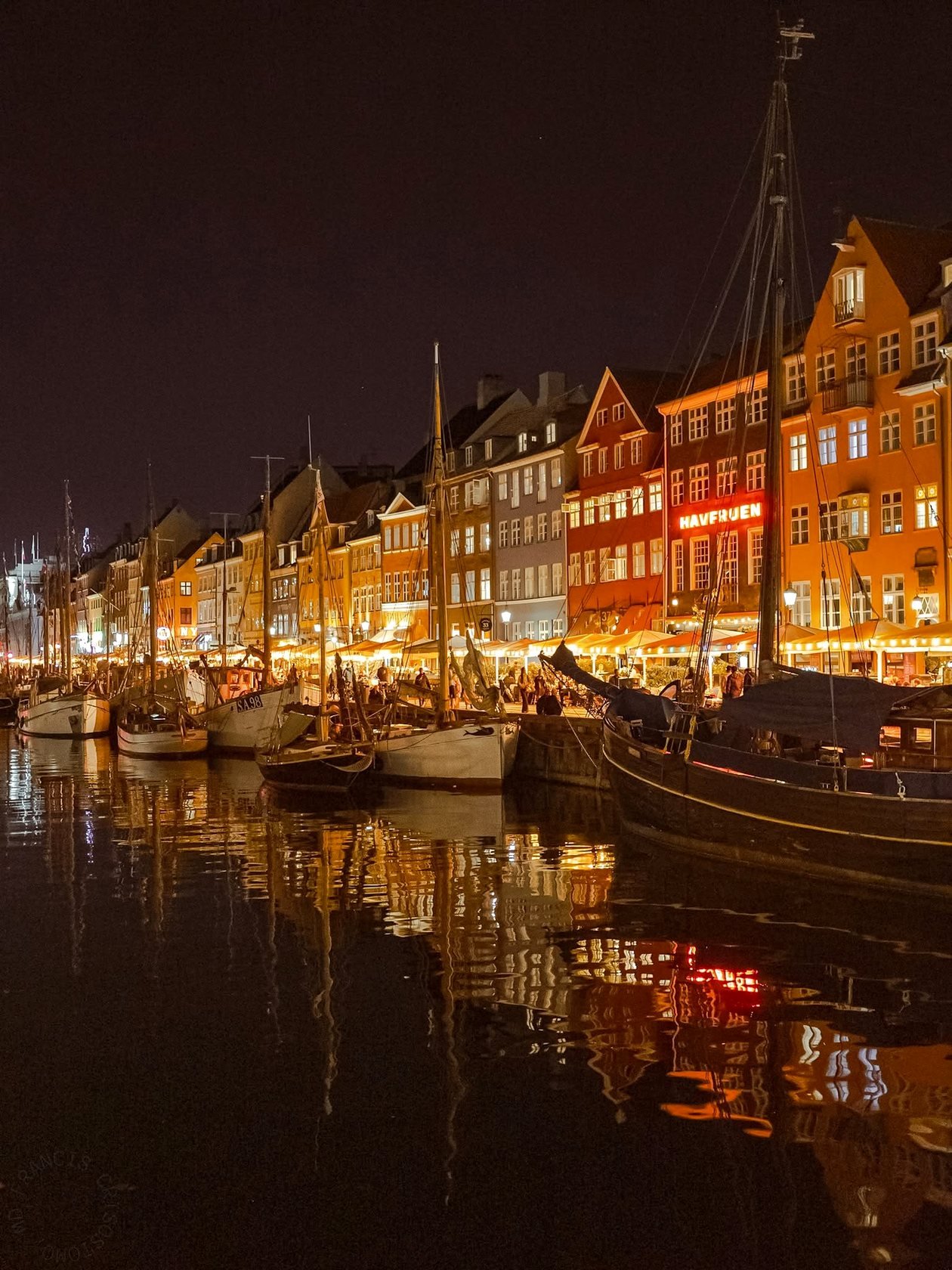 Nyhavn iluminado à noite, com as casas refletidas no canal