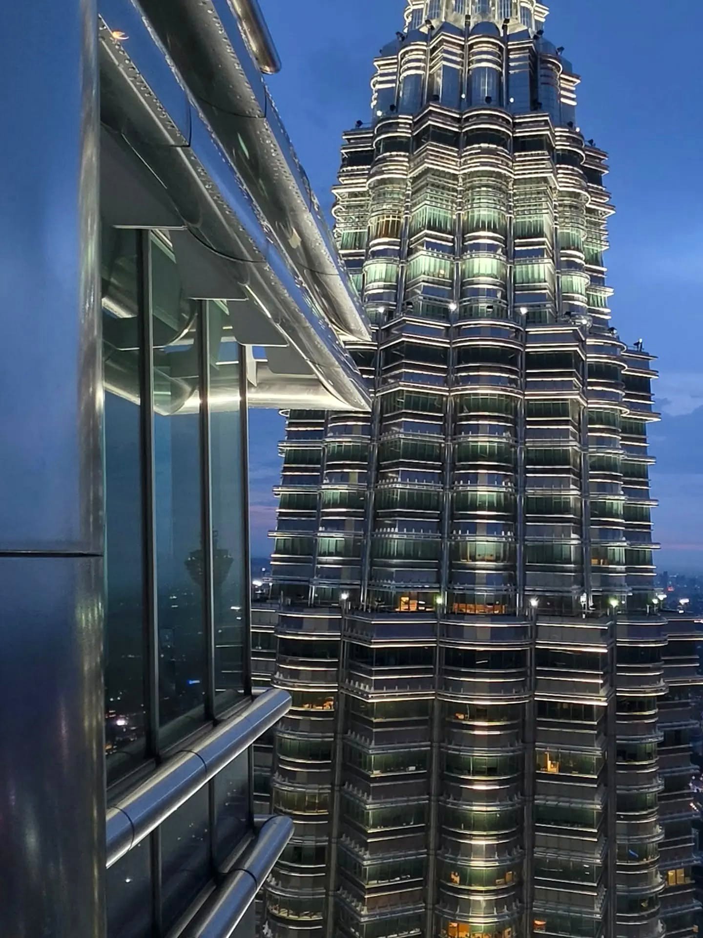 Detalhe de uma das Torres Petronas iluminada, vista do alto da outra torre