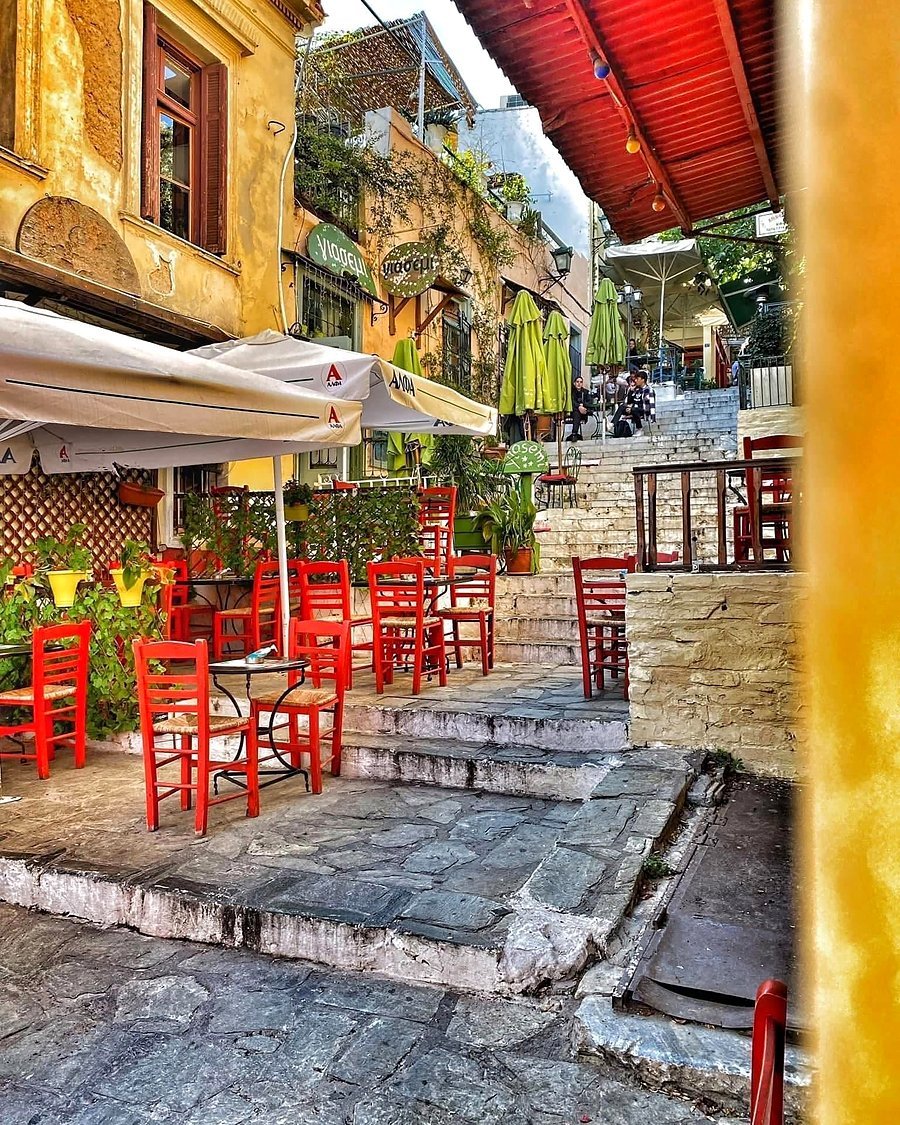 Mesas de taverna com cadeiras vermelhas em uma escadaria de Plaka, em Atenas