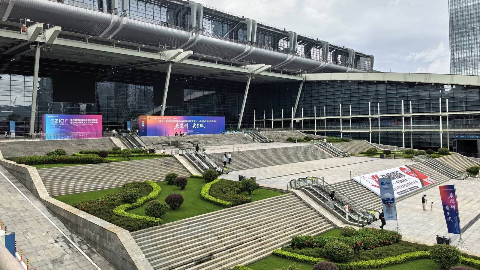 Área externa de um centro de exposições de Shenzhen, com escadarias e painéis de feiras