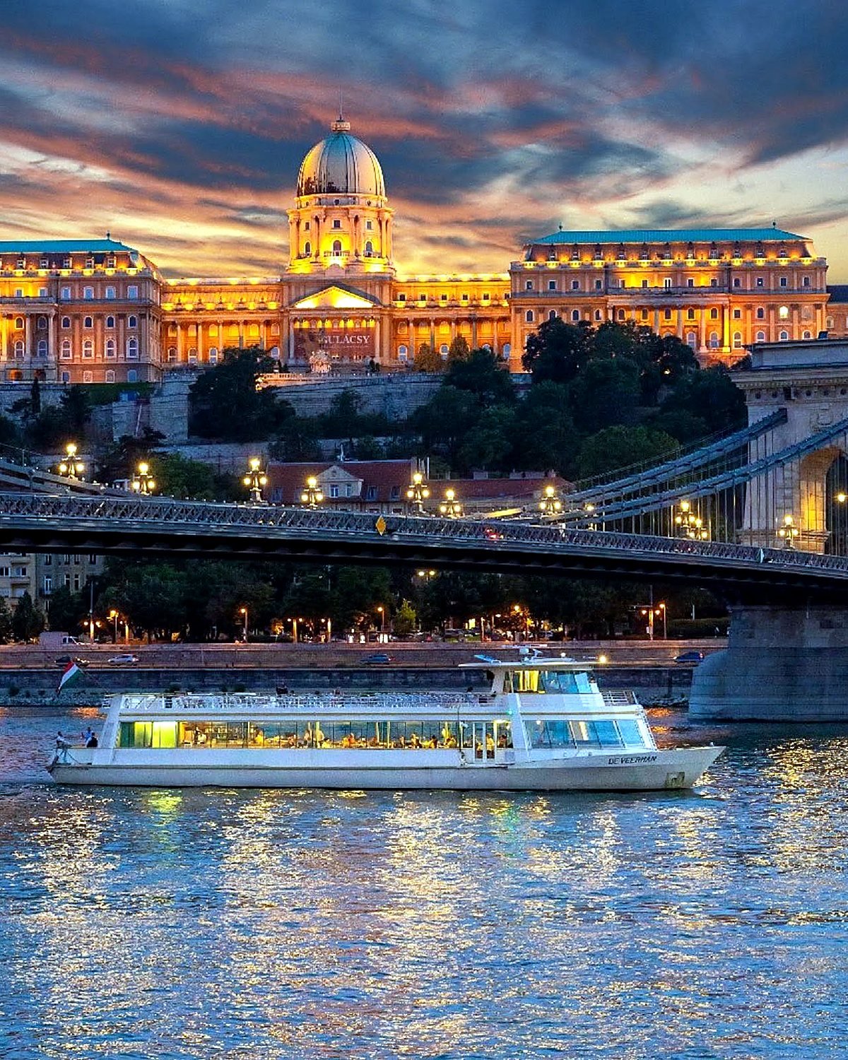Barco de passeio no Danúbio em frente ao Castelo de Buda iluminado