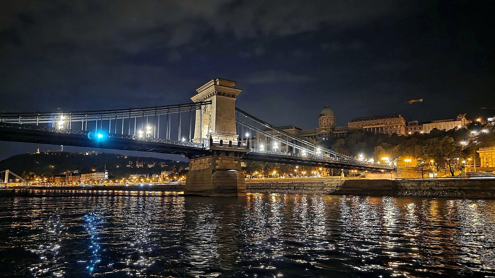 Ponte das Correntes e Castelo de Buda iluminados à noite, vistos do Danúbio