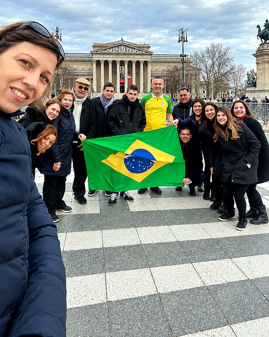 Agnes com grupo de turistas brasileiros e a bandeira do Brasil na Praça dos Heróis