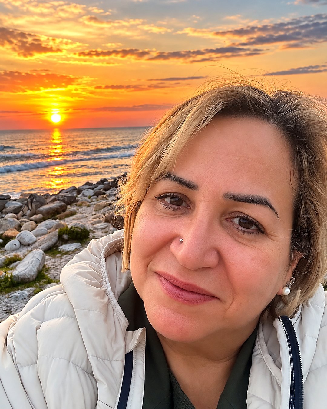 Bia, guia brasileira na África do Sul, sorrindo à beira-mar ao pôr do sol