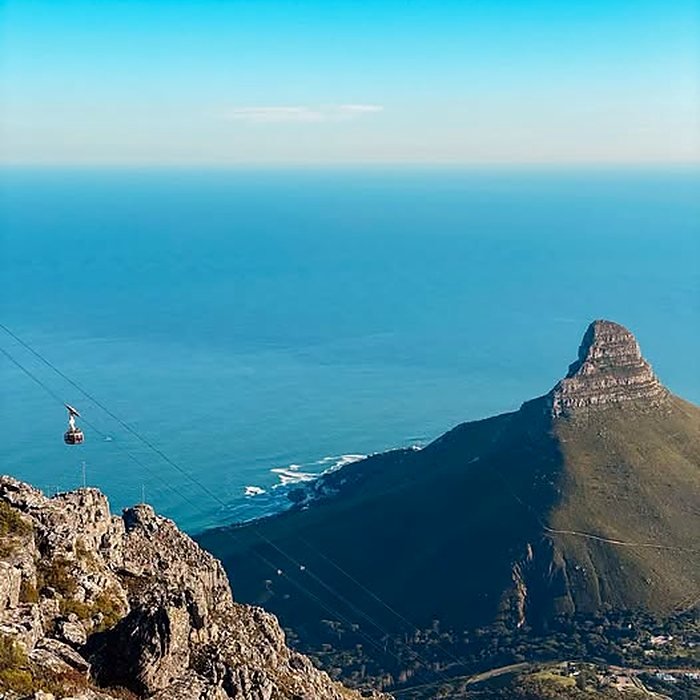 Bondinho subindo a Table Mountain com o Lion's Head e o oceano ao fundo