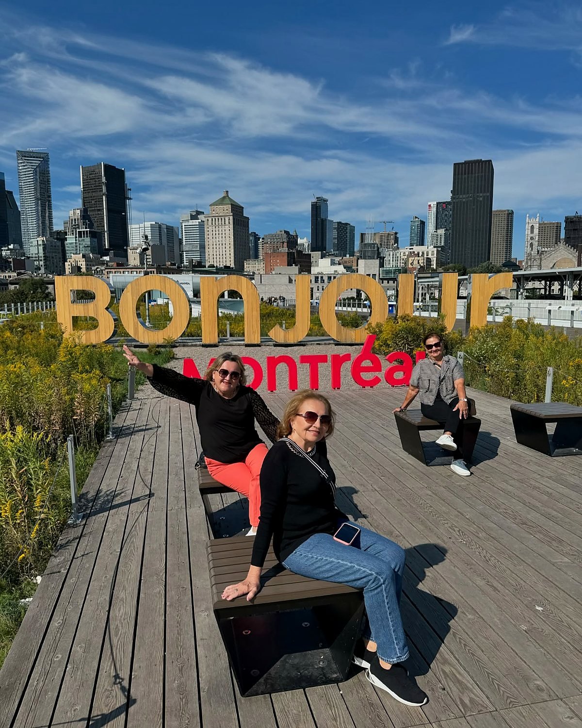 Viajantes brasileiras no letreiro Bonjour Montréal, no Vieux-Port, com o centro da cidade ao fundo