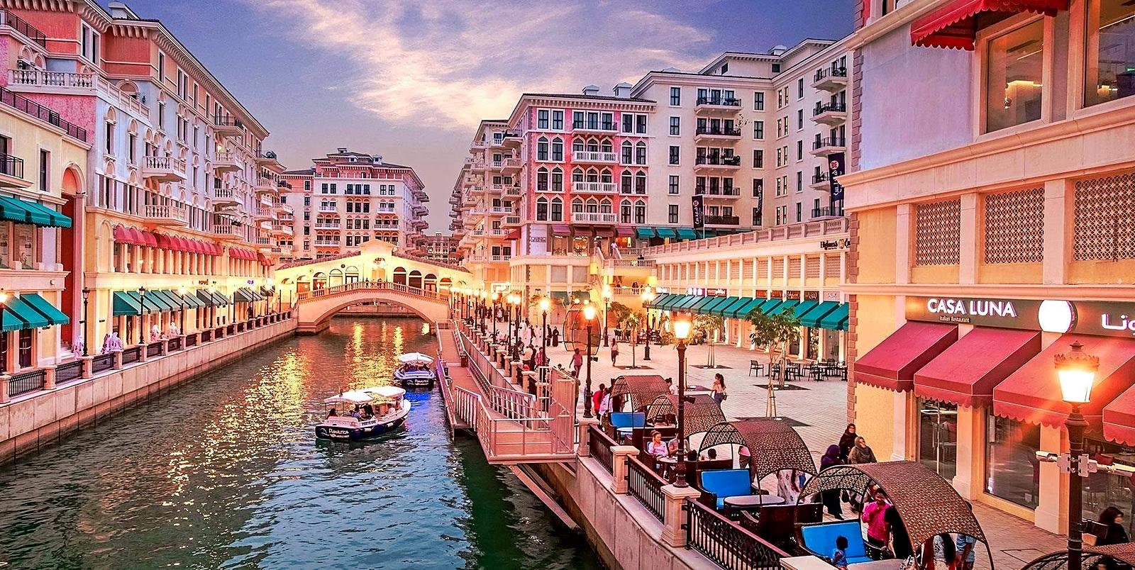 Canal e prédios coloridos do Qanat Quartier ao entardecer