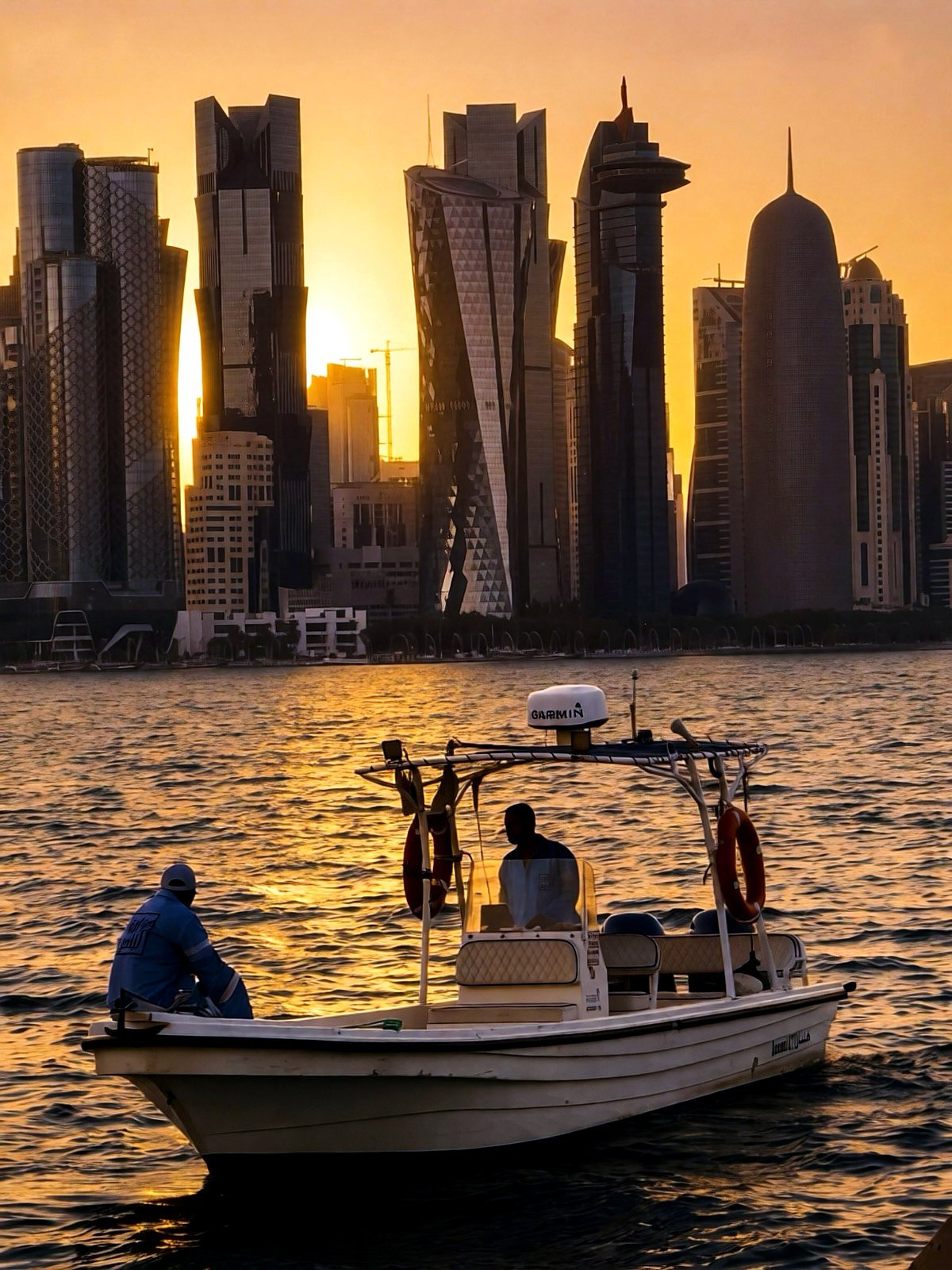 Barco na baía com o skyline de West Bay ao pôr do sol