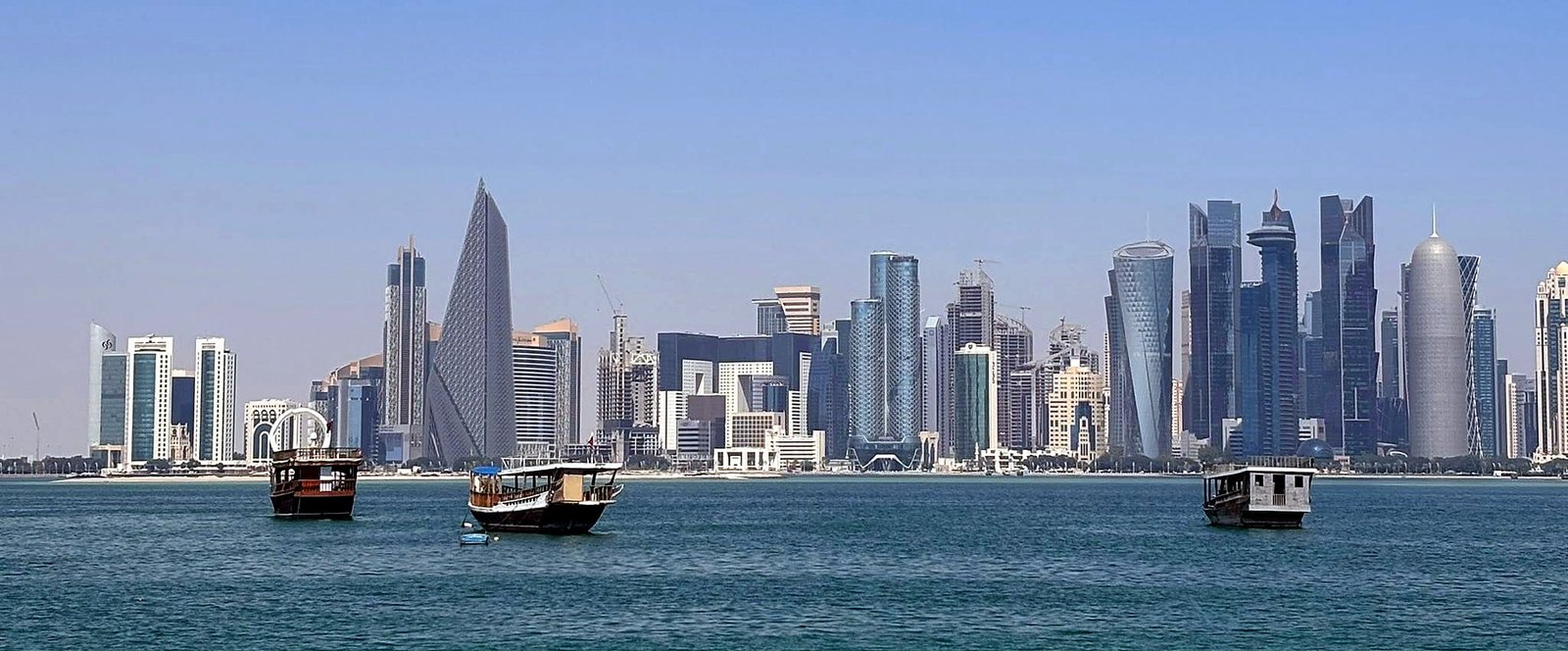 Barcos dhow na baía de Doha com o skyline de West Bay