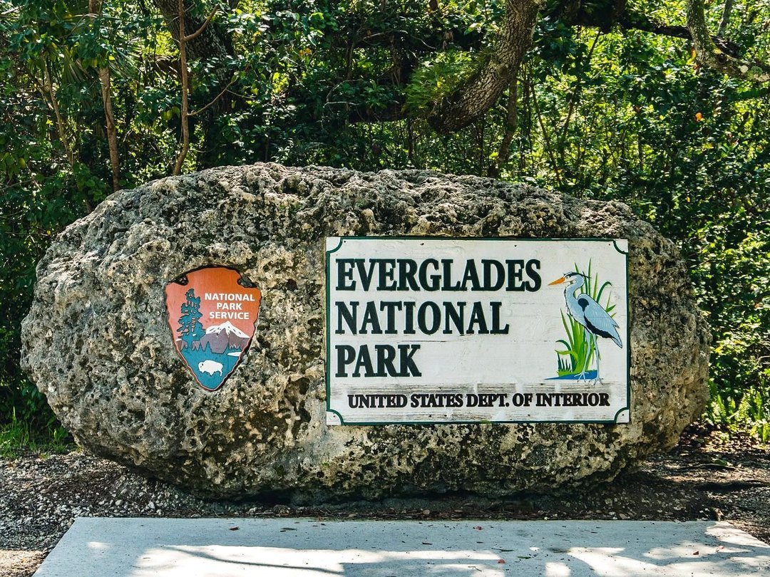 Placa do Everglades National Park esculpida em uma grande rocha, cercada de vegetação