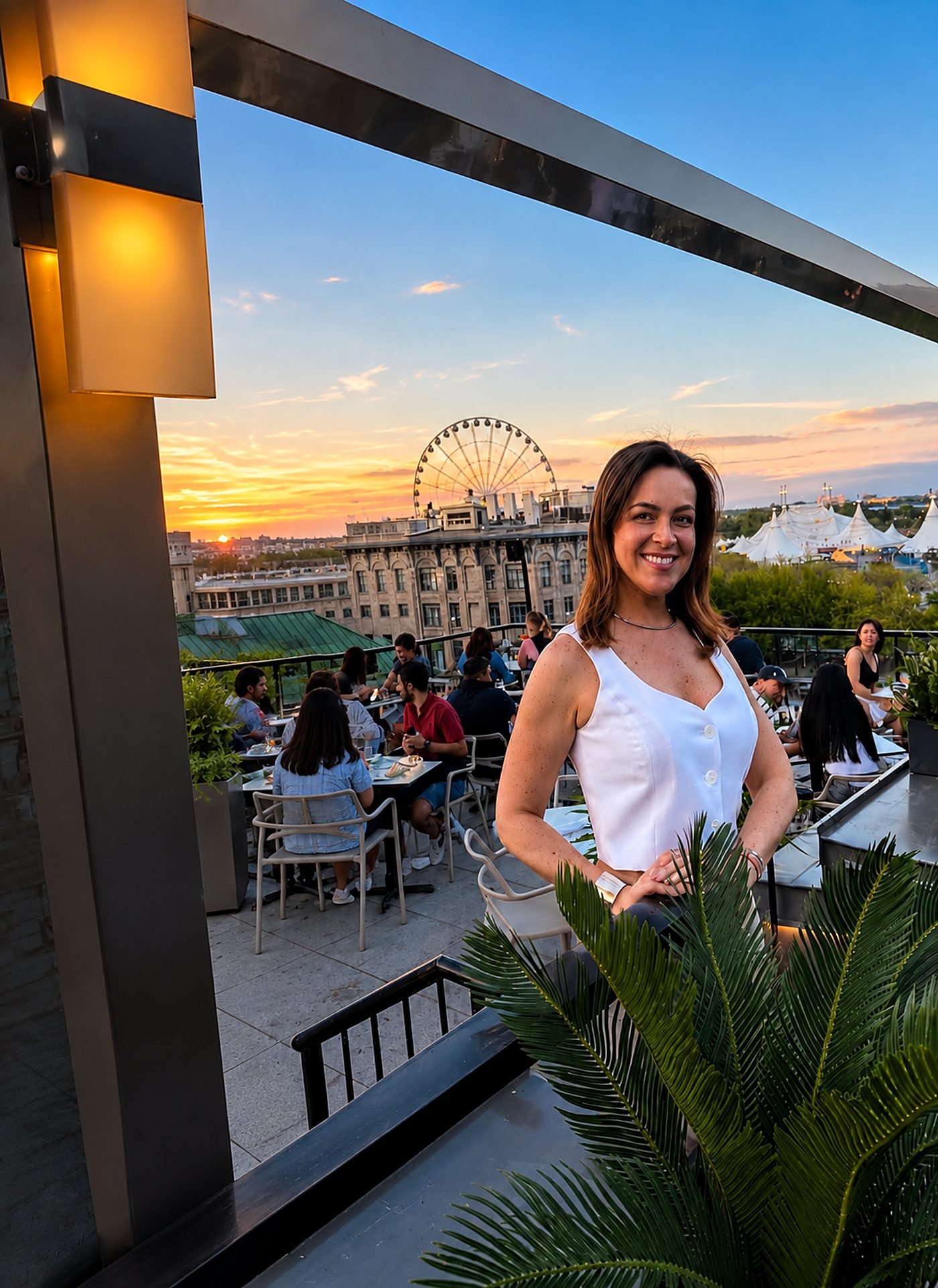 Leila Diniz, guia brasileira em Montreal, em um terraço ao pôr do sol, com a roda-gigante do Vieux-Port ao fundo