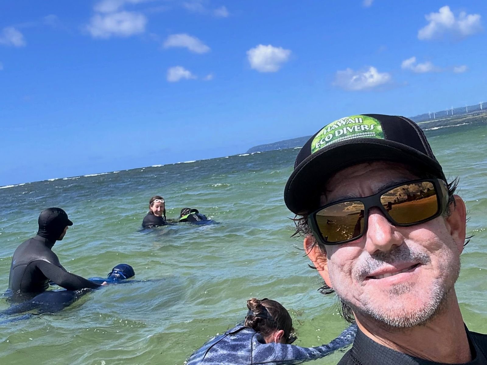 Ricardo Taveira, guia brasileiro e instrutor, no mar do North Shore com alunos ao fundo