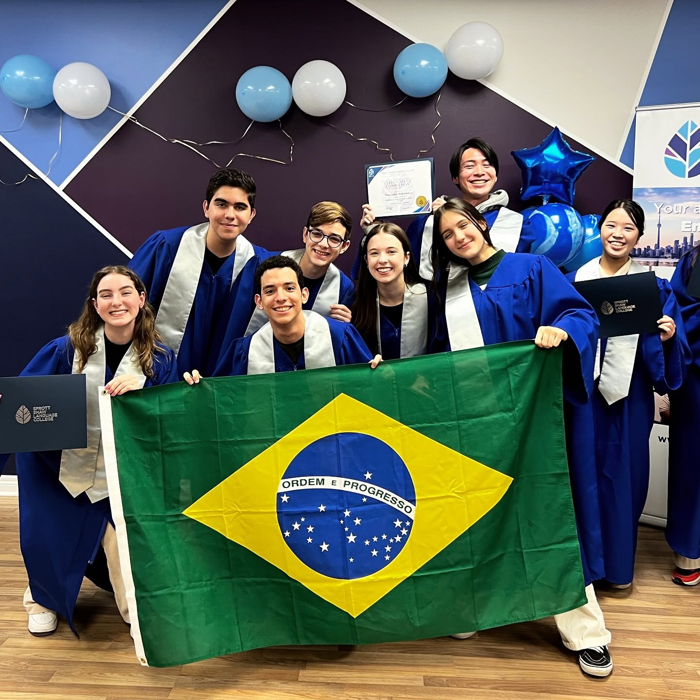 Estudantes brasileiros de intercâmbio com a bandeira do Brasil na formatura do curso no Canadá