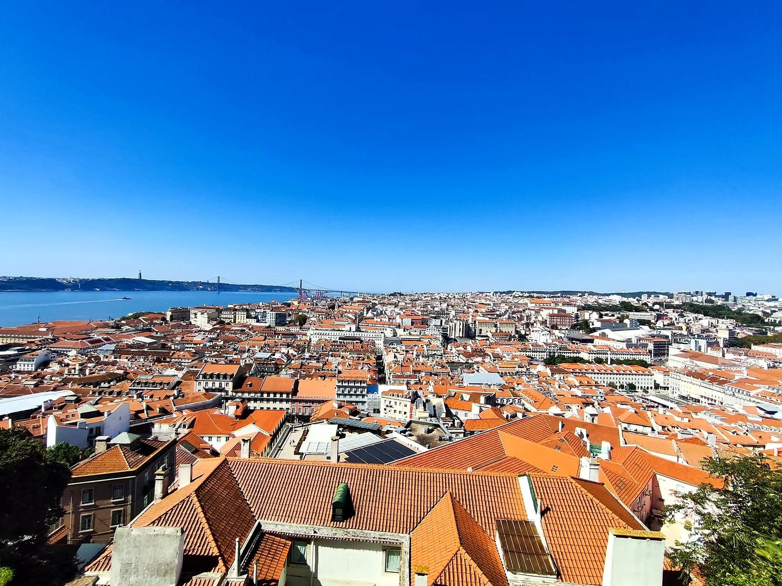 Vista panorâmica dos telhados de Lisboa, com o Rio Tejo e a Ponte 25 de Abril