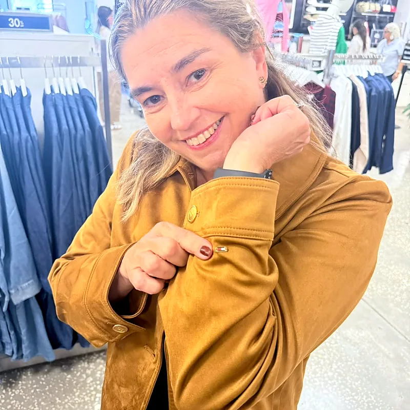 Débora mostrando detalhes de acabamento de uma jaqueta em loja de outlet de Orlando