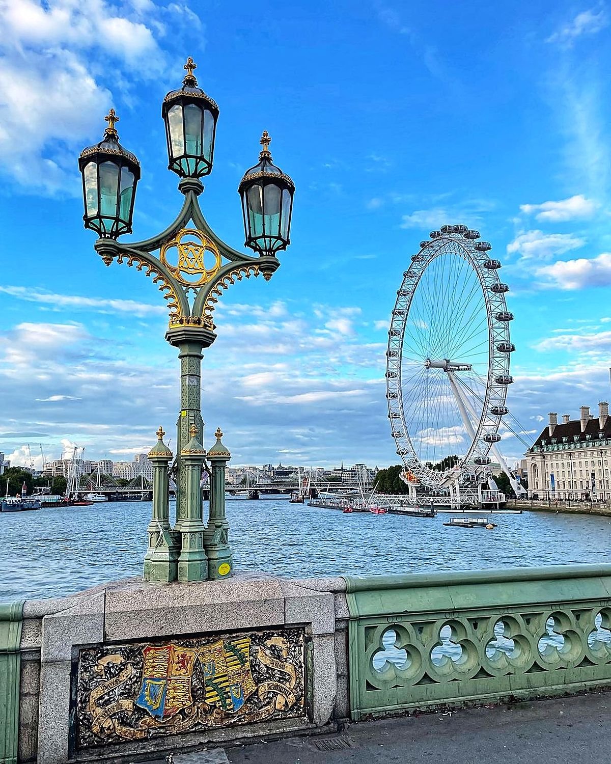 Poste histórico da Ponte de Westminster com a London Eye e o rio Tâmisa ao fundo