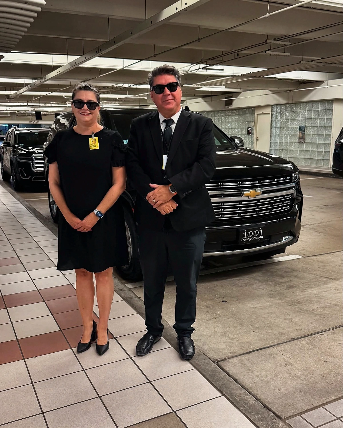 Marcelo e Débora, da 1001 Transportation, uniformizados ao lado de uma SUV preta