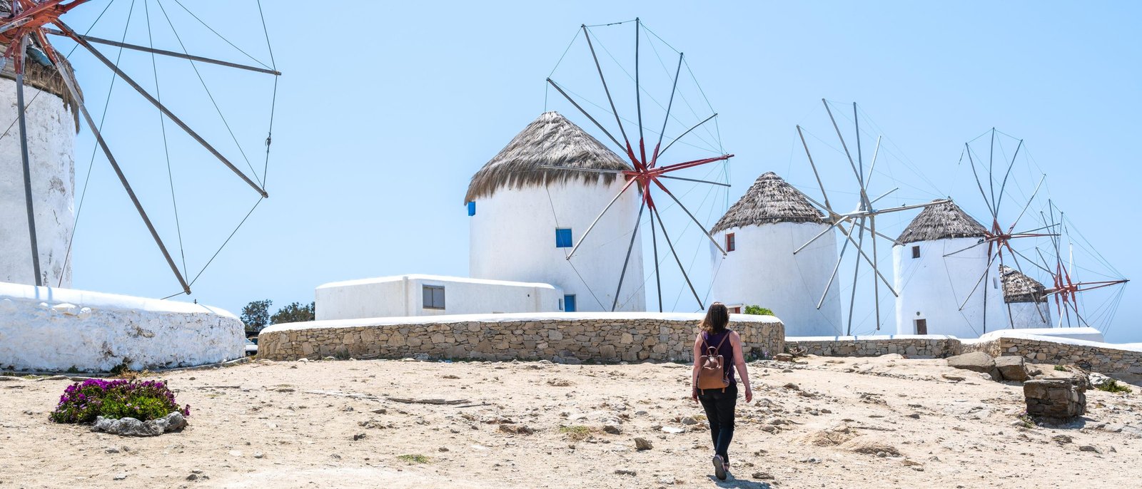 Fileira de moinhos de vento brancos de Kato Mili, em Mykonos, com uma visitante caminhando em frente