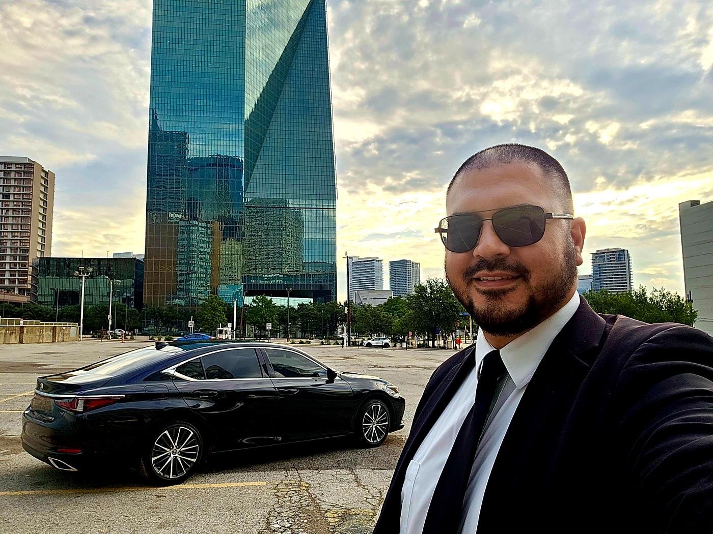 Alisson Guimarães com o sedã executivo e os prédios do centro de Dallas ao fundo