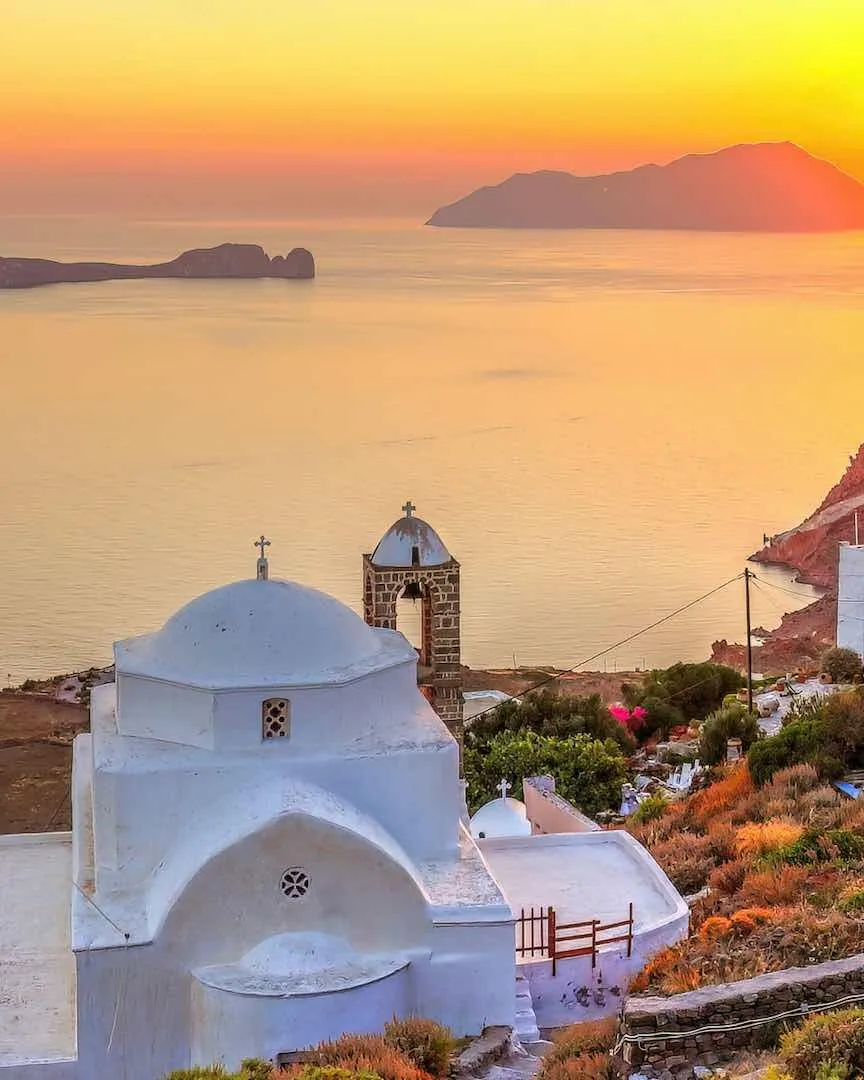 Pôr do sol visto do alto do Kastro de Plaka, em Milos, com a igreja branca e o mar Egeu ao fundo