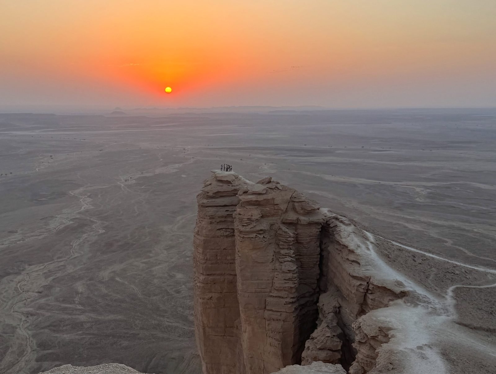 Penhasco do Edge of the World sobre a planície do deserto ao pôr do sol