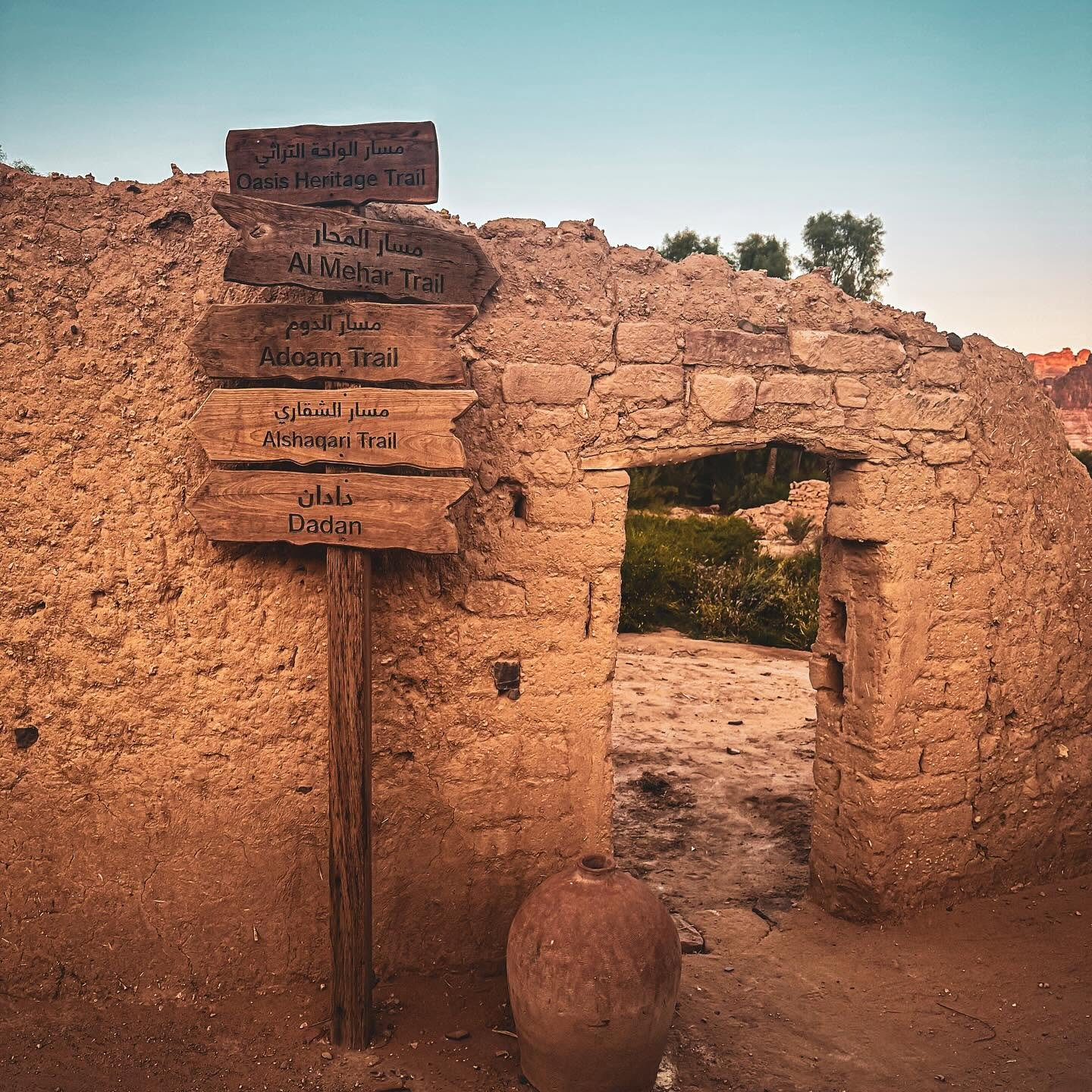 Placas de trilhas e muro de adobe no oásis de AlUla