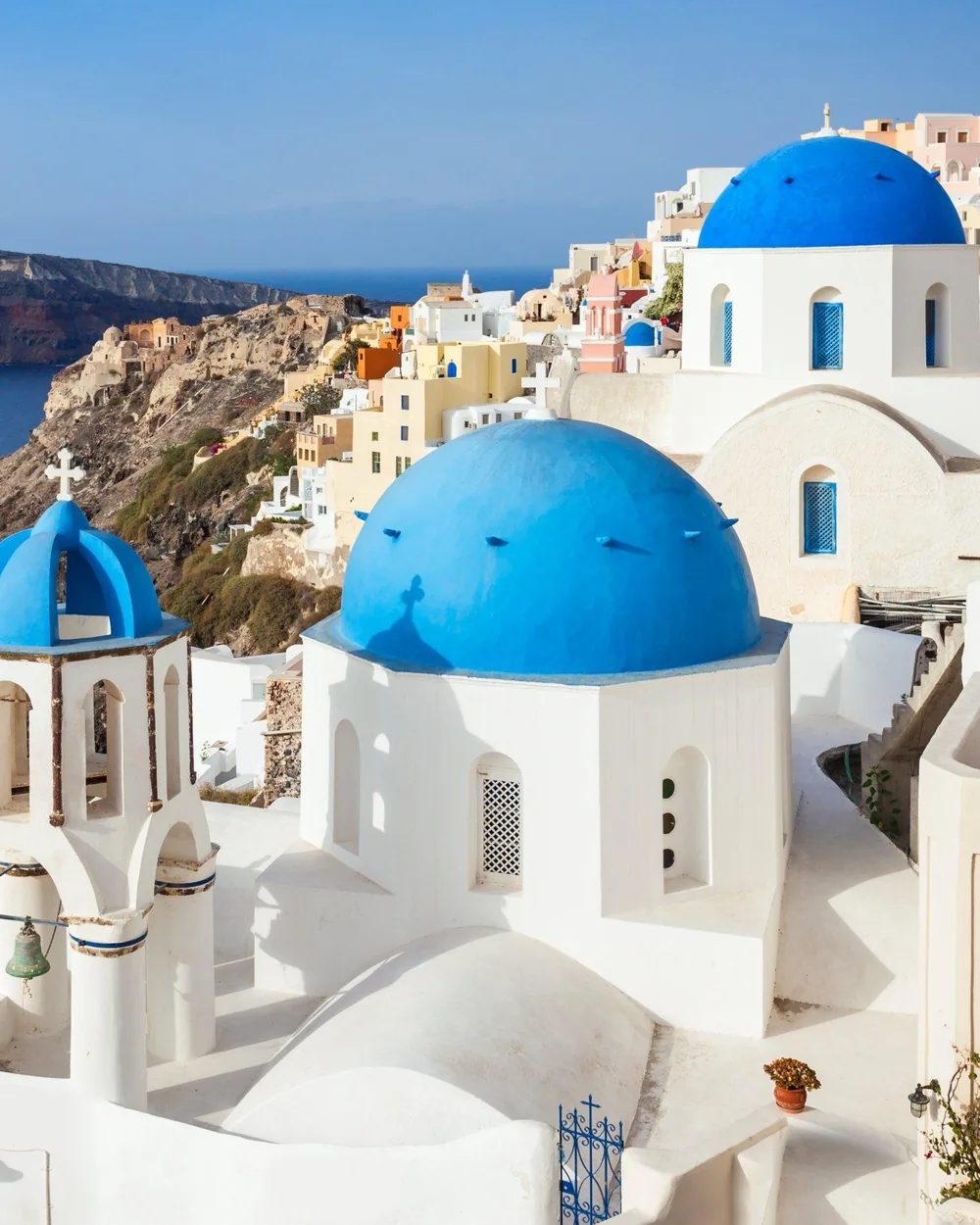 Igrejas de cúpula azul em Oia, Santorini, com a caldeira e o mar ao fundo