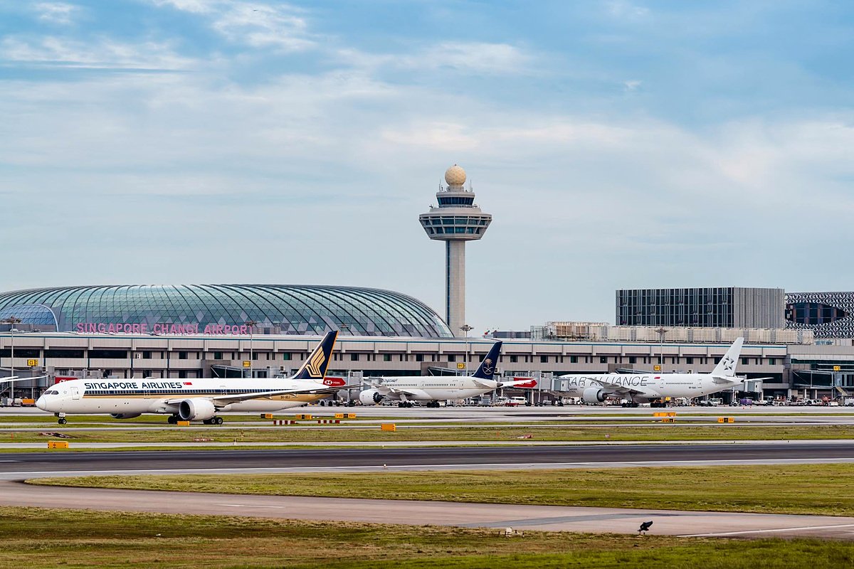Aviões no pátio do aeroporto de Changi, com a torre de controle e o Jewel ao fundo