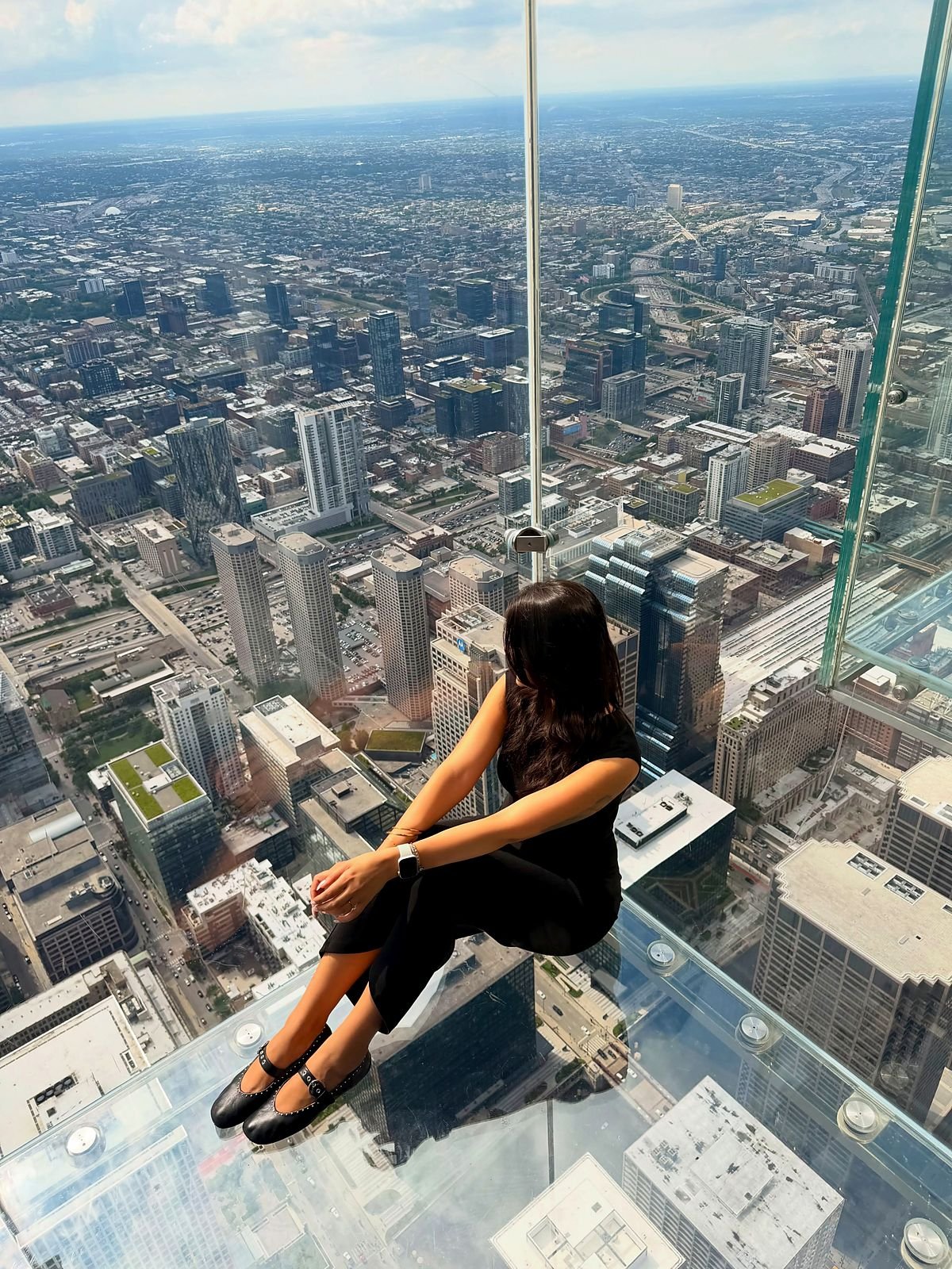 Visitante sentada na varanda de vidro do Skydeck, na Willis Tower