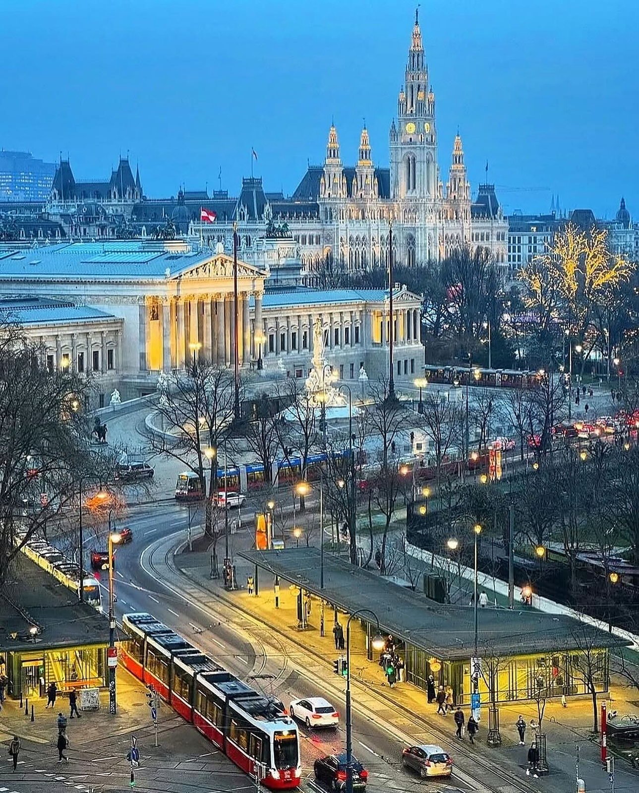 Prefeitura e Parlamento de Viena iluminados no fim de tarde, com bondes na Ringstrasse