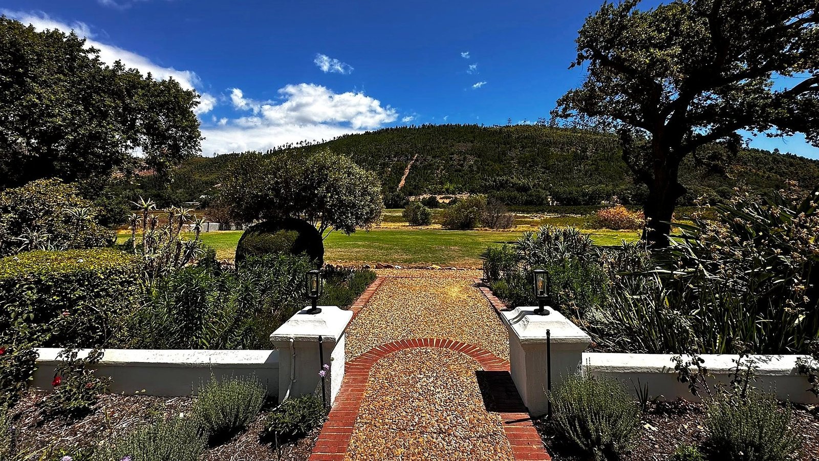 Jardim de uma vinícola histórica em Stellenbosch com montanhas ao fundo