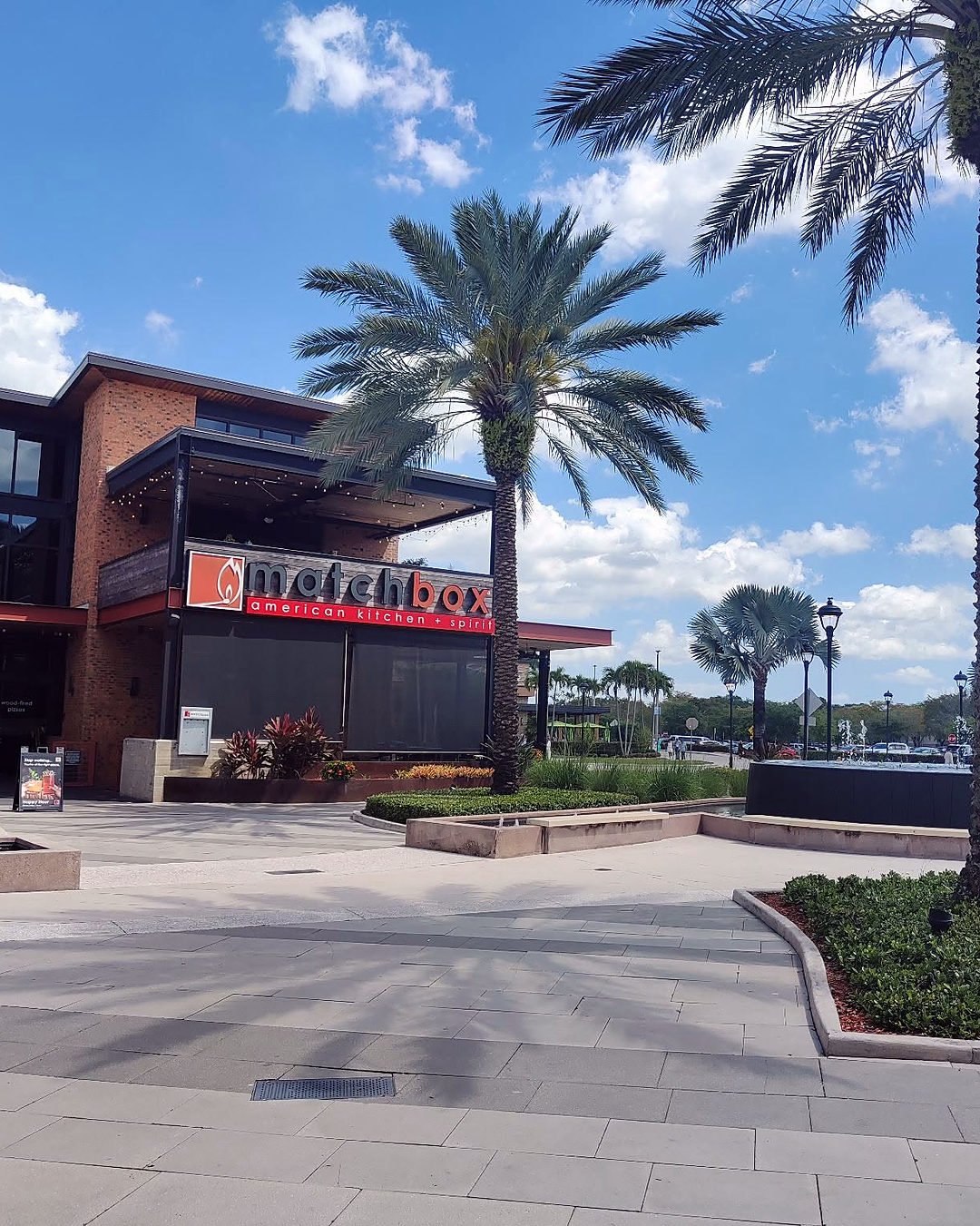 Área ao ar livre do Sawgrass Mills, com palmeiras, fonte e restaurantes