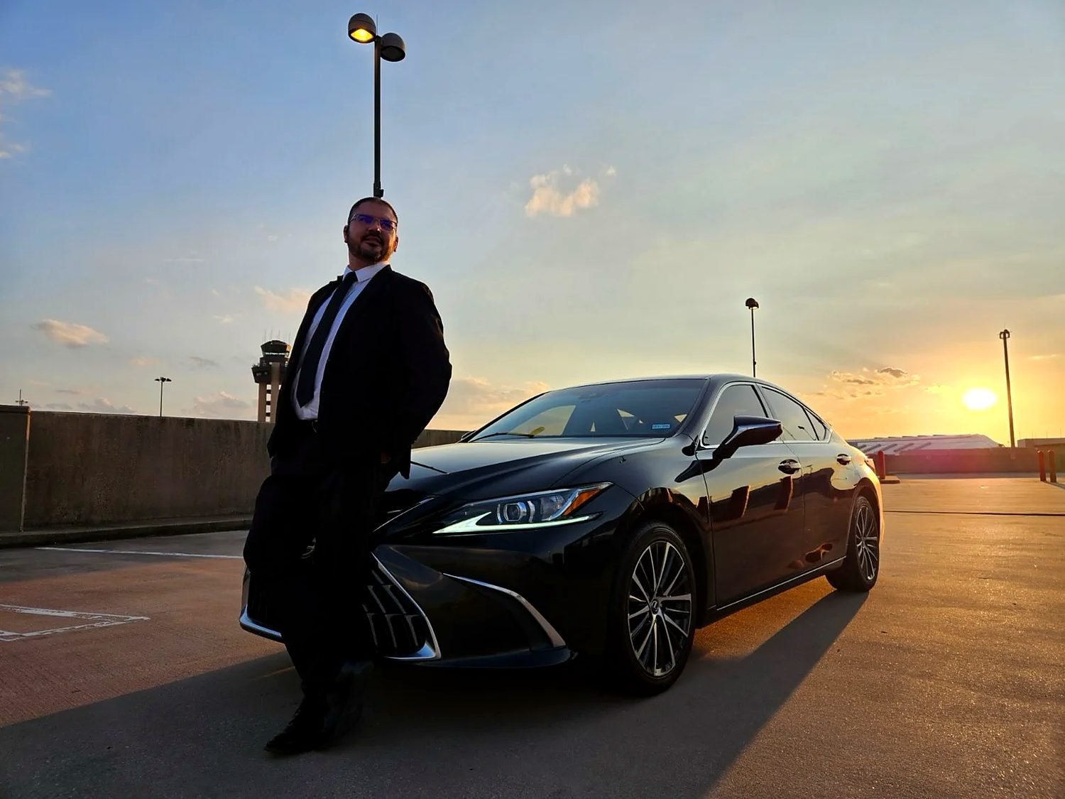 Alisson Guimarães ao lado do sedã executivo, no fim de tarde em Dallas