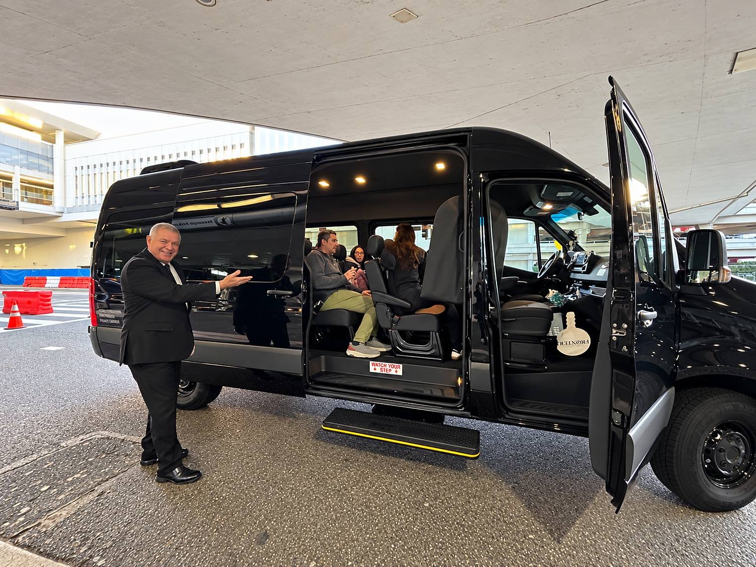 Motorista da GS Transportation recebendo passageiros ao lado da van no aeroporto de Los Angeles