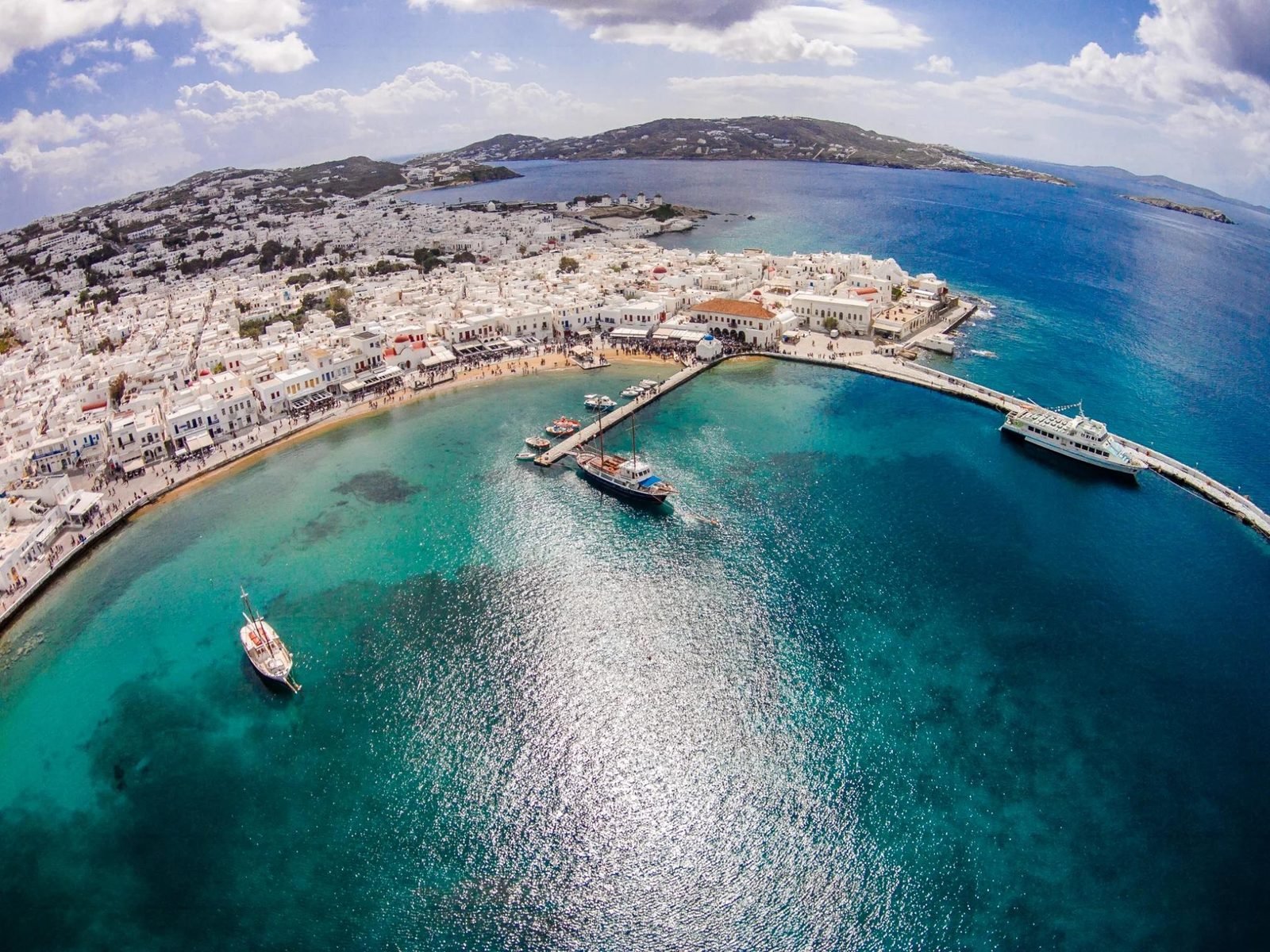 Vista aérea de Chora, com as casas brancas, a praia e o porto de Mykonos