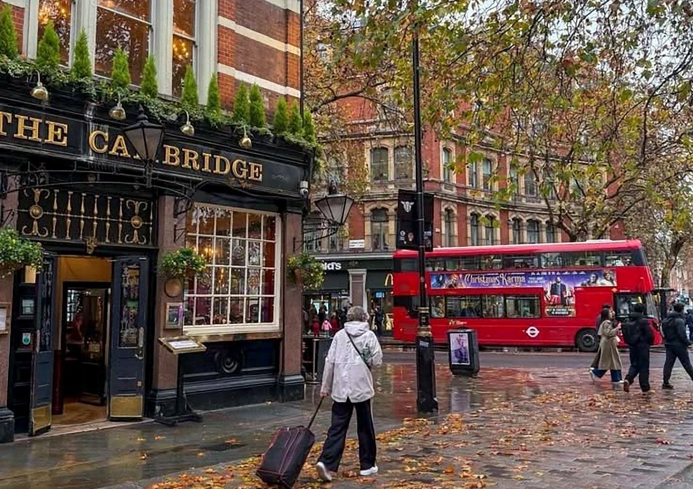 Rua de Londres no outono com folhas no chão molhado, pub tradicional e ônibus vermelho
