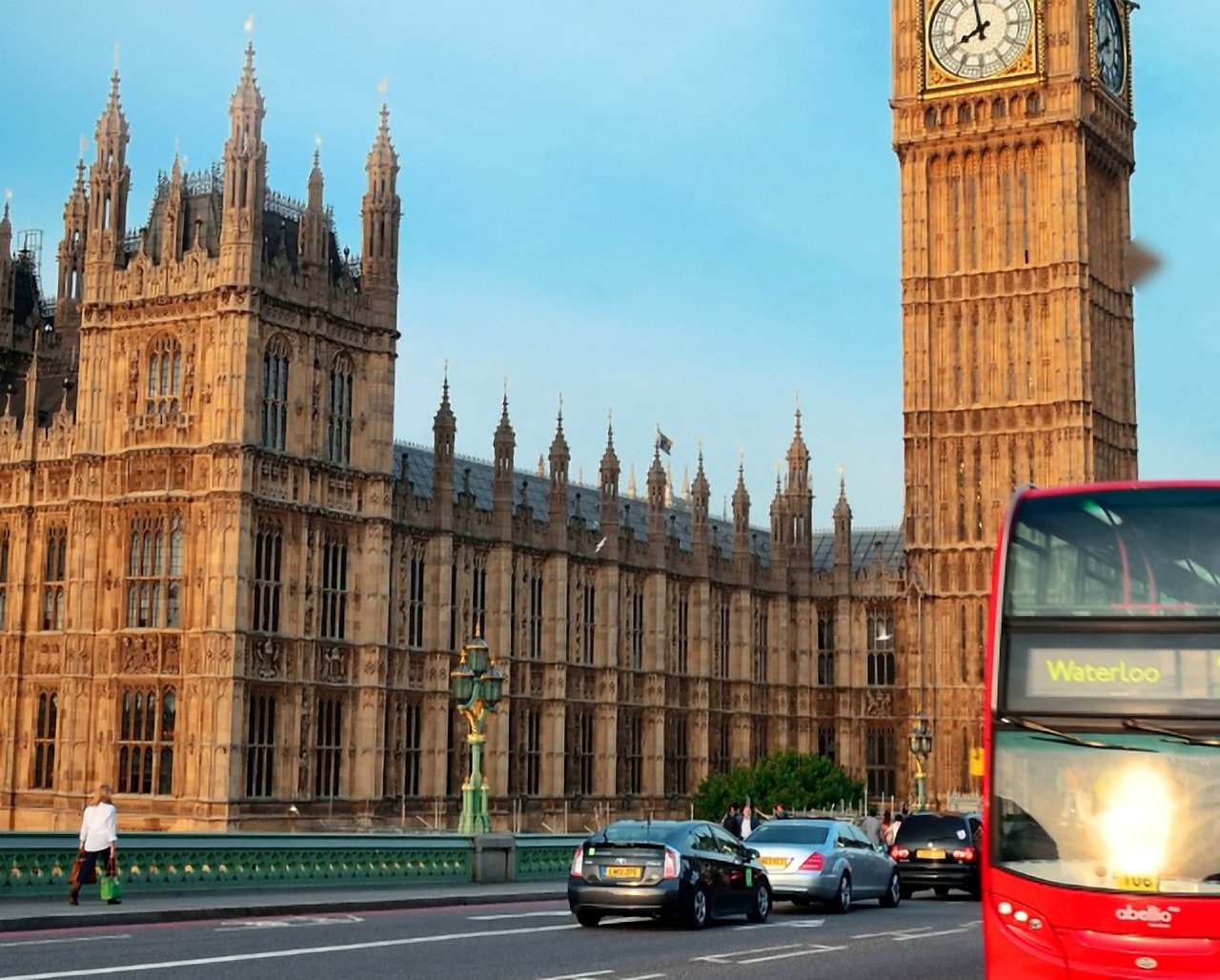 Big Ben e Parlamento com céu azul e ônibus vermelho de dois andares na ponte de Westminster