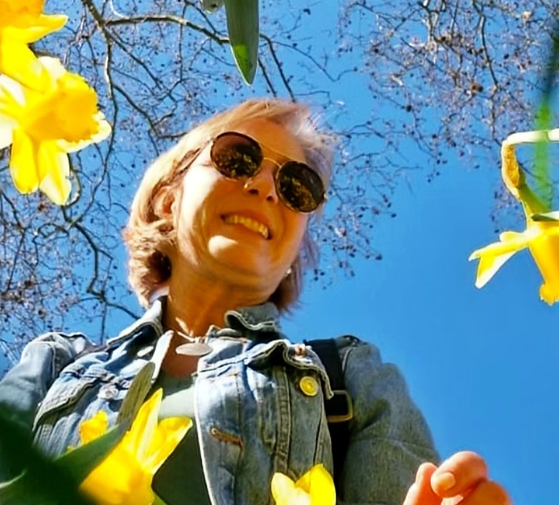 Rita Castelan, guia brasileira em Londres, sorrindo entre narcisos amarelos