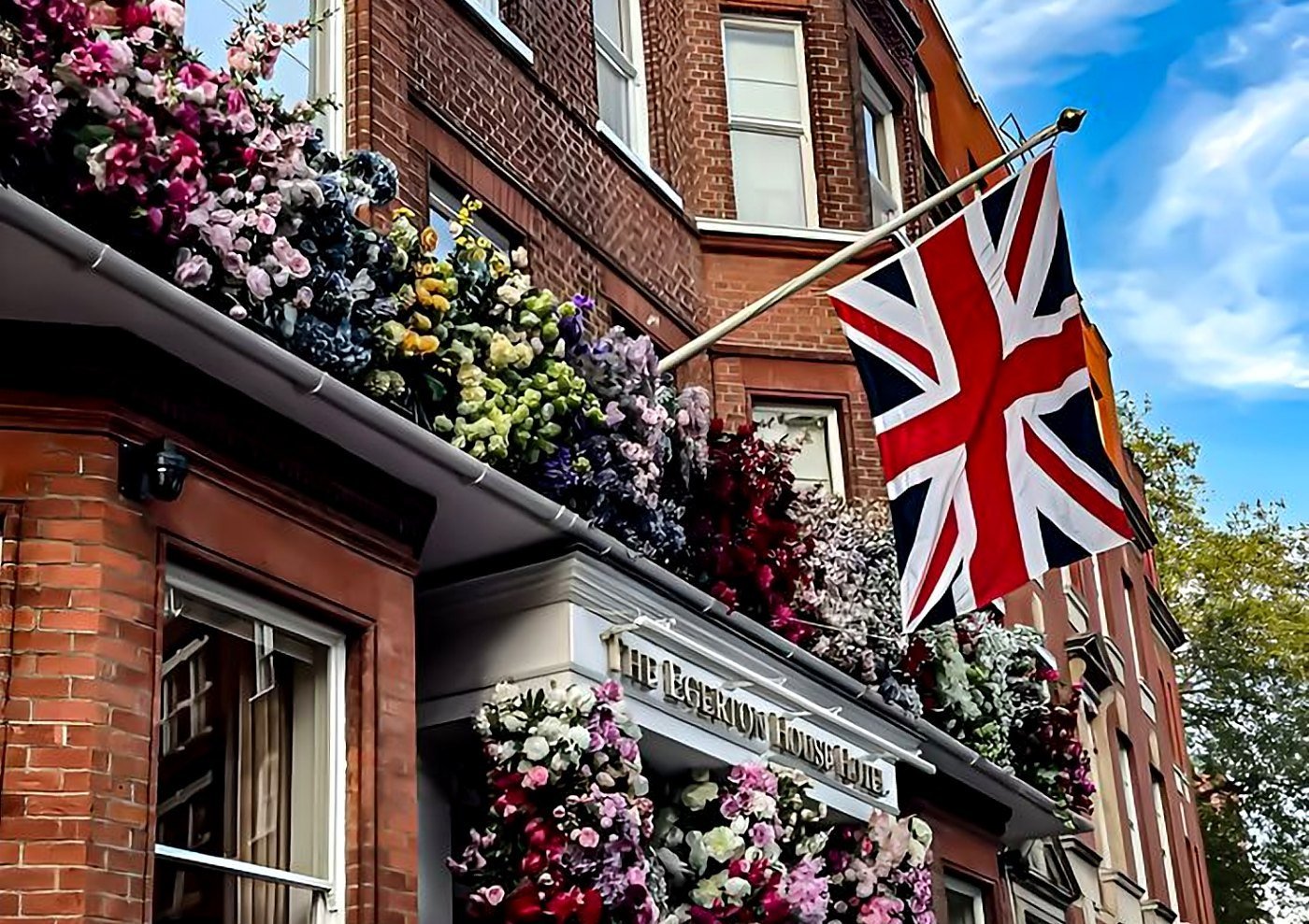 Fachada de tijolos coberta de flores e bandeira do Reino Unido em Kensington na primavera