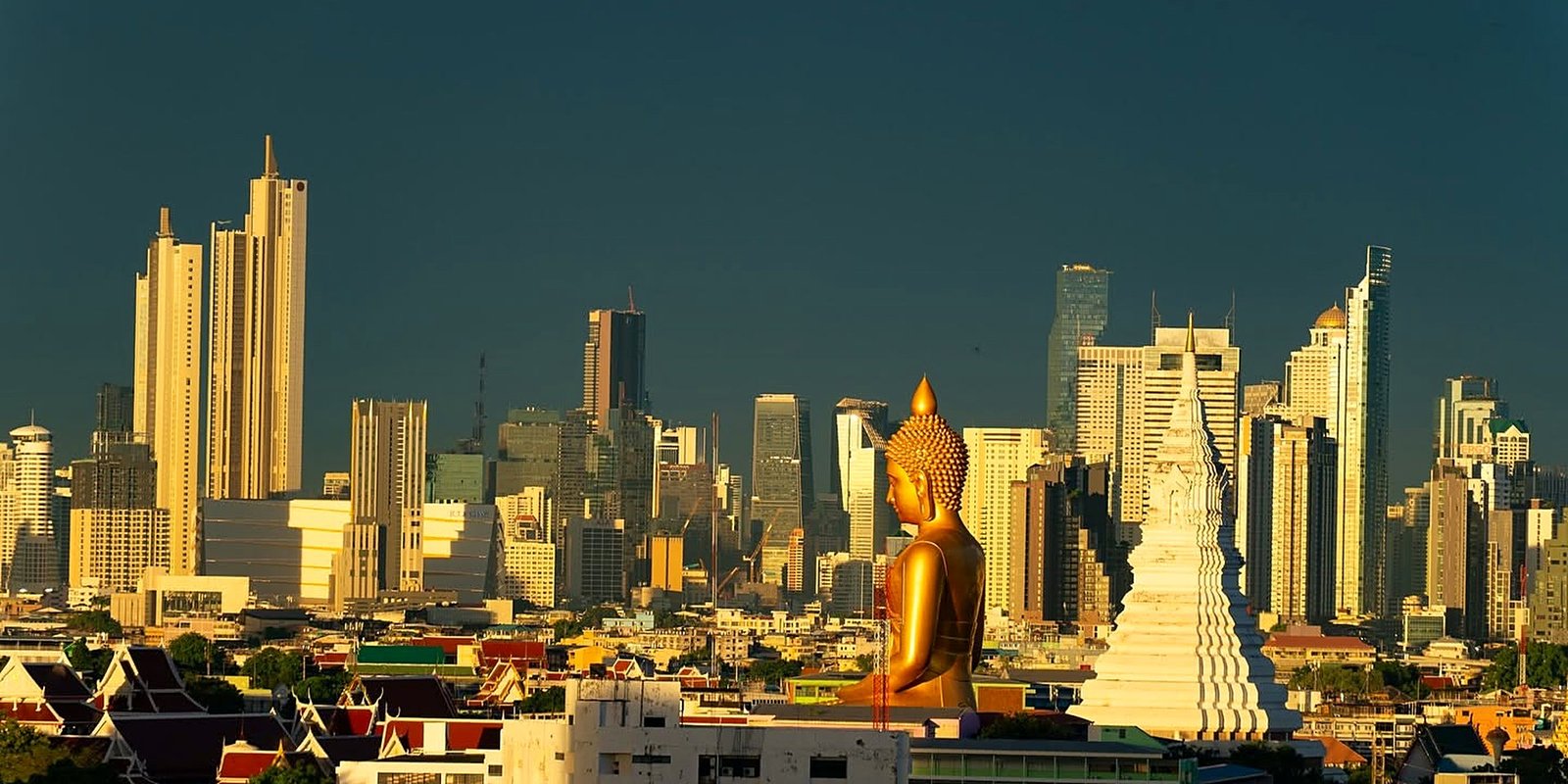 Horizonte de Bangkok com arranha-céus e o Buda dourado gigante do Wat Paknam ao entardecer