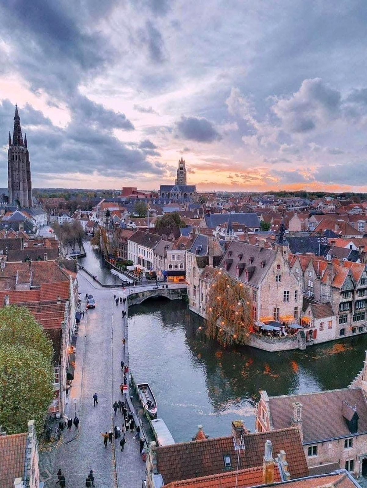 Vista aérea de Bruges ao pôr do sol, com o canal do Rozenhoedkaai, barcos e as torres da cidade