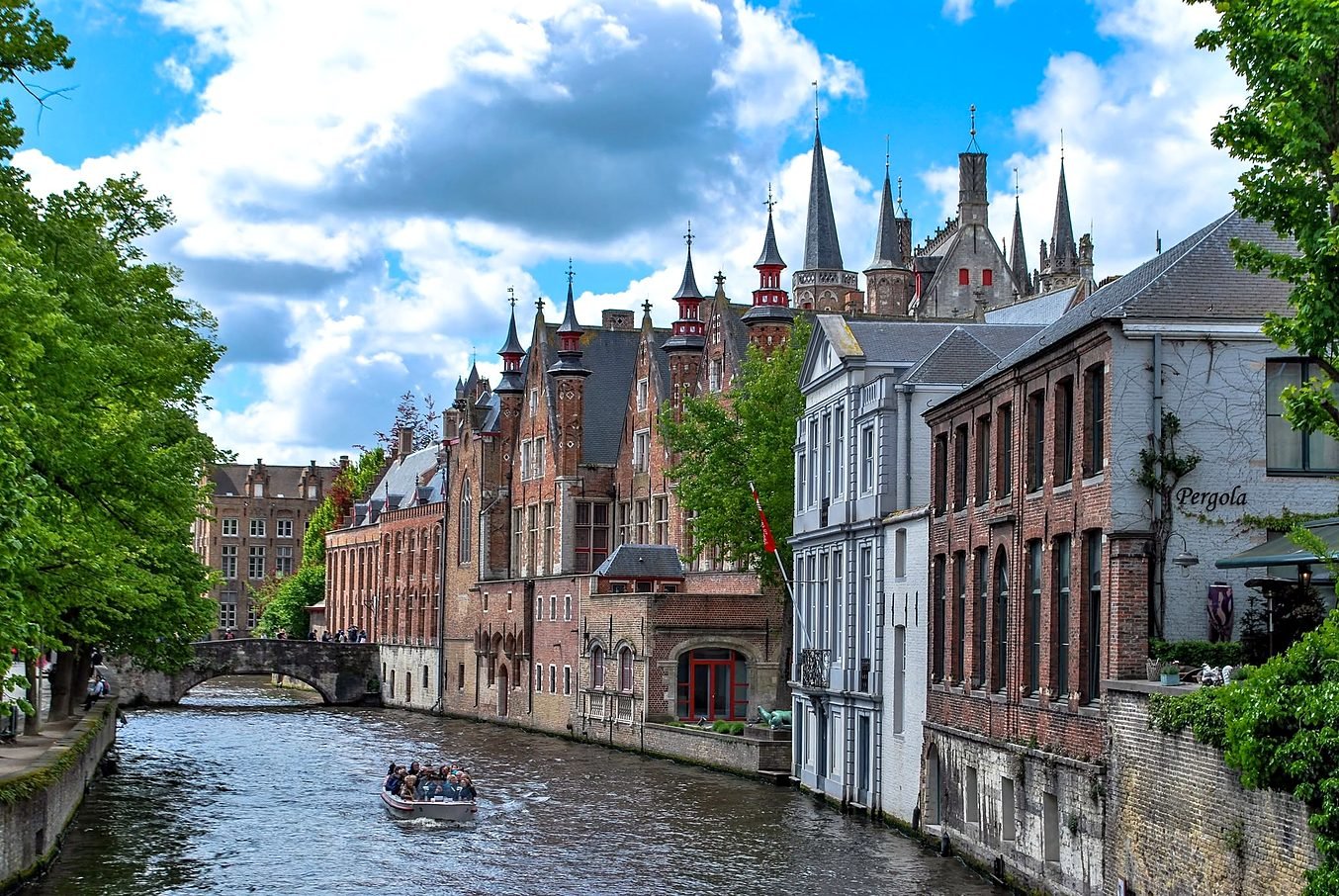 Canal de Bruges com casas medievais e barco turístico
