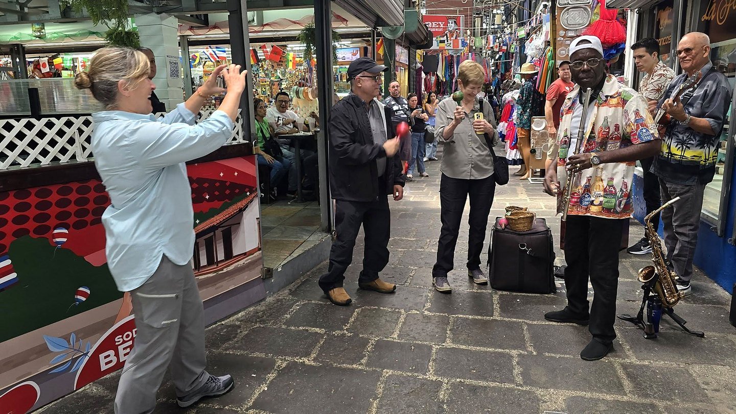 Corredor do Mercado Central de San José com músicos de rua e turistas