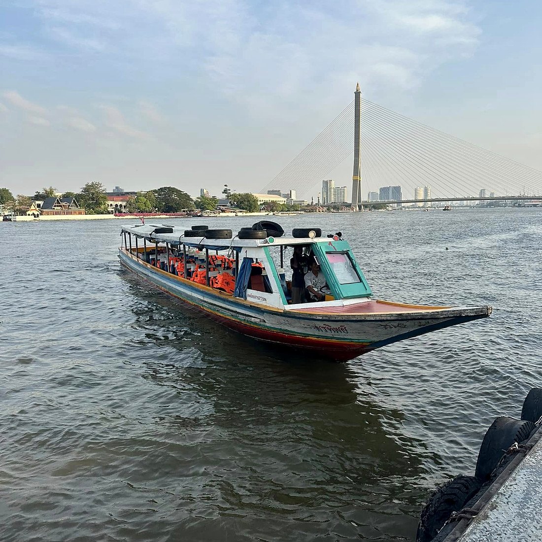 Barco de passageiros no rio Chao Phraya com a ponte Rama VIII ao fundo, em Bangkok
