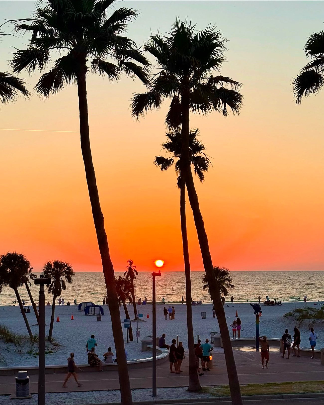 Pôr do sol entre coqueiros em Clearwater Beach, com areia branca e o Golfo do México