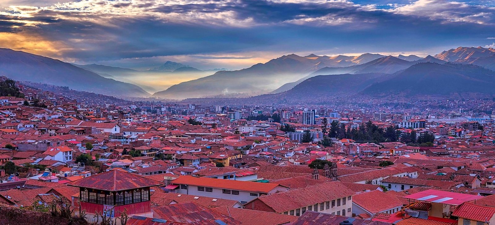 Vista panorâmica de Cusco com os telhados vermelhos e o vale andino ao amanhecer