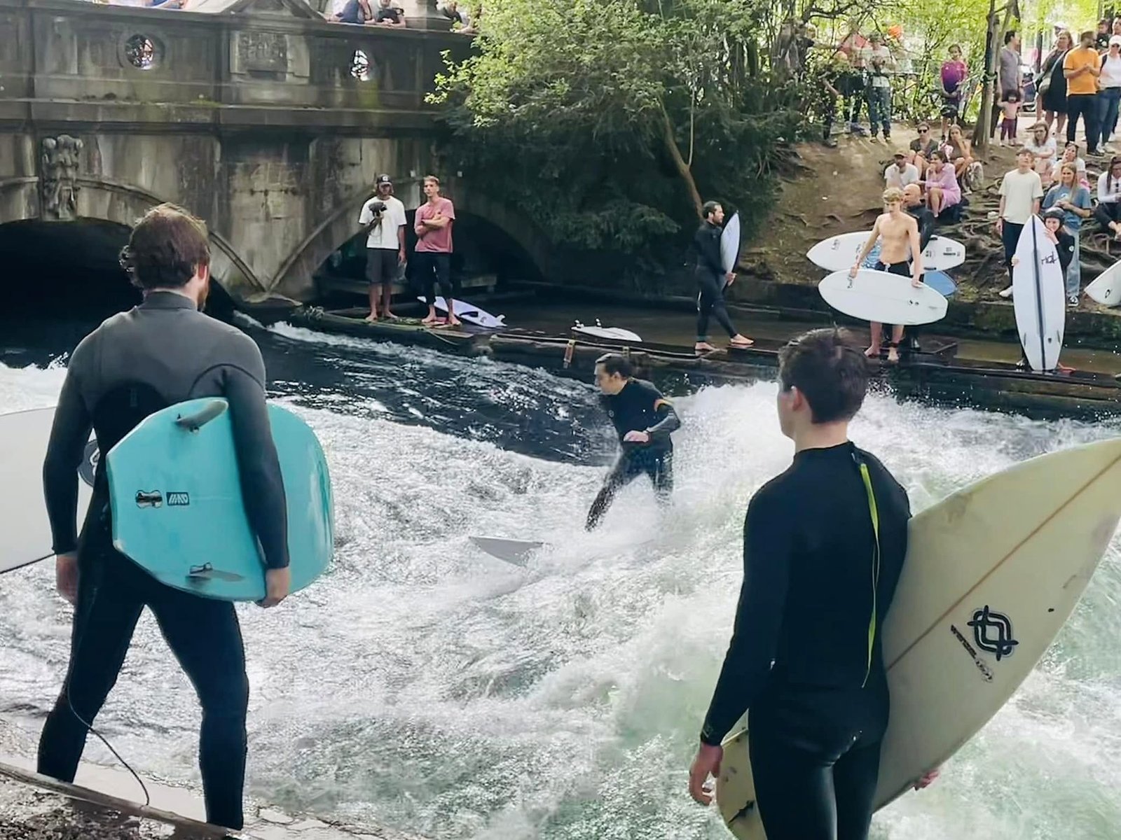 Surfistas na onda do rio Eisbach no Jardim Inglês de Munique