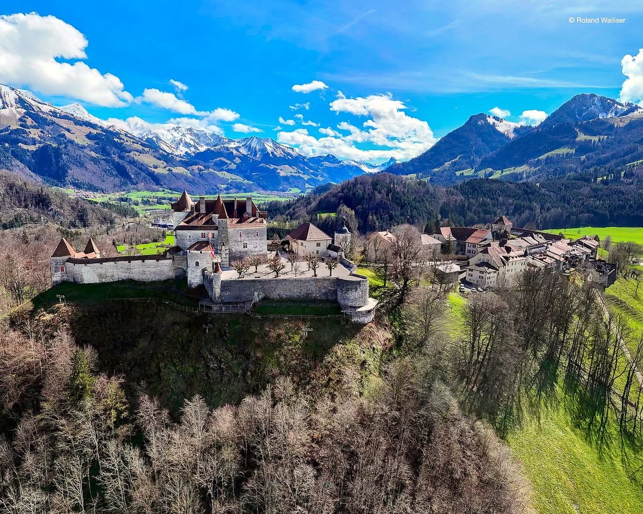 Castelo de Gruyères e vilarejo medieval no alto da colina com os Alpes nevados